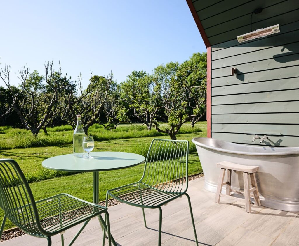 Outdoor bath tub and table and chairs on a cabin balcony area