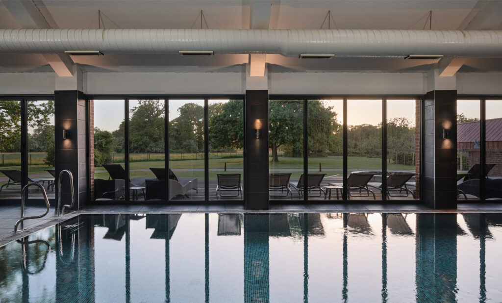 View of pool, deck chairs and gardens outside