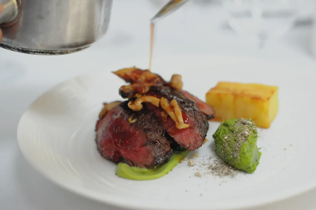 Luxury plate of food being topped with sauce by a chef