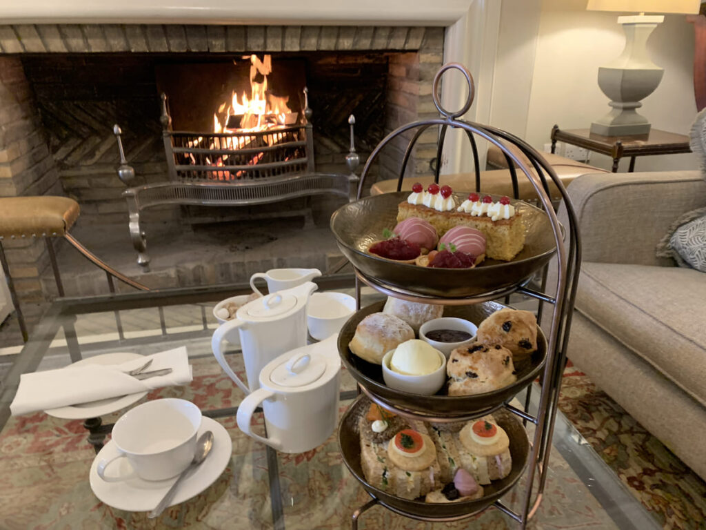 An afternoon tea stand with buns, scones, sandwiches, teapots and teacups