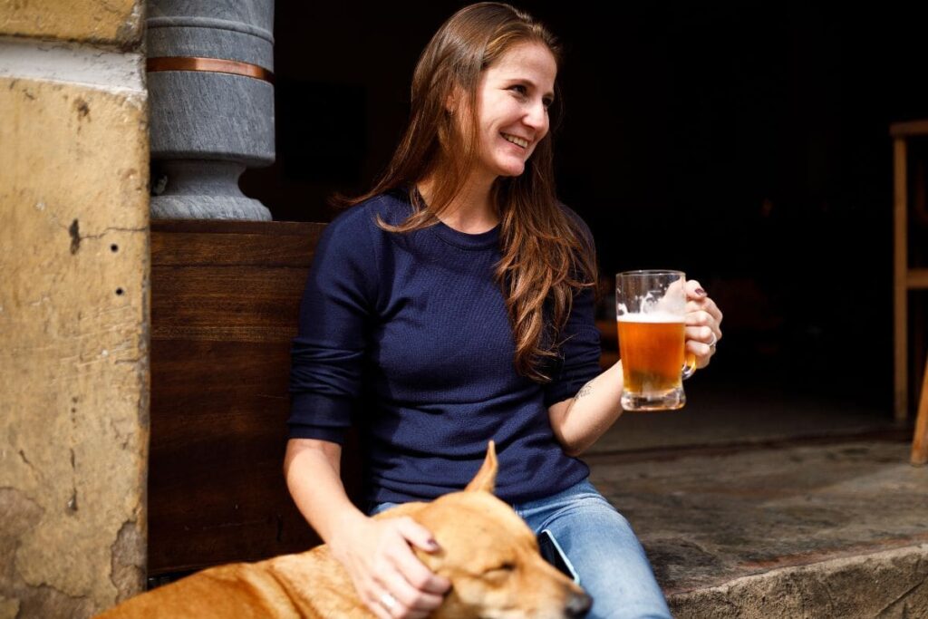 Preppy Countryside lady drinking a pint of beer with her dog outside a dog friendly pub in kings lynn